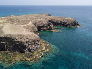 Vista aerea delle coste frastagliate e delle spiagge di Lanzarote, Spagna, Canarie.  Bagnanti in spiaggia e nell’Oceano Atlantico. Papagayo