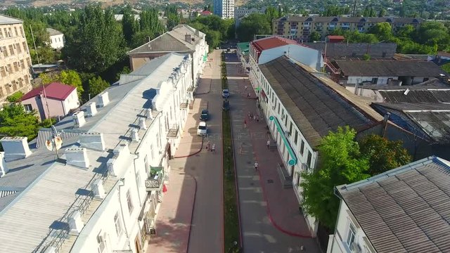 Aerial top view Feodosia fly in drone street city centre view aero sity Crimea, fishing town, fountain square, people walking, filmed from old city Lermontov Feodosia. Crimea vacation on Black sea.