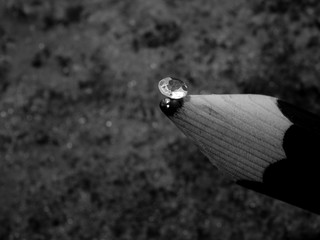 A Single Small Diamond on the Tip of a Lead Pencil Showing the Facet Cut of the Gem Stone, with a Blurred Sparkle Black and White Stone Background