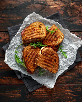 grilled sandwich with turkey, bacon, tomato and cheese on rustic wooden background