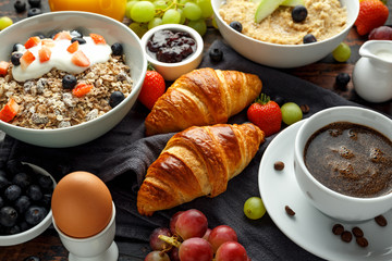 Healthy Breakfast served with coffee, orange juice, croissants, egg, cereals, oatmeal and fruits.