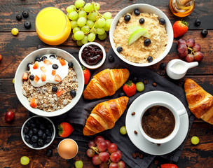 Healthy Breakfast served with coffee, orange juice, croissants, egg, cereals, oatmeal and fruits.