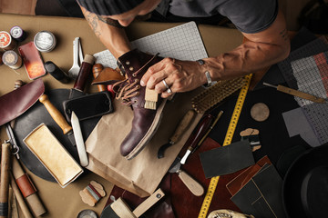 Enjoying process of creation custom made shoes. Workplace of shoe designer. Hands of shoemaker...