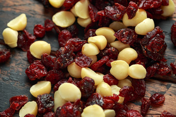 Healthy snack of Dried cranberries and macadamia nuts in a ceramic bowl on rustic wooden table