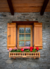 Fototapeta na wymiar alpine architecture window with red flower and window shutters