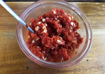 Small transparent bowl of crushed tomatoes with a spoon served to enhance food flavors.