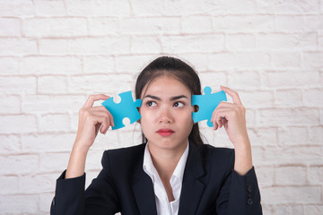 serious pensive business girl holding jigsaw pieces , thinking for the ideas