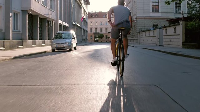 Behind young man swerving with his bicycle on the city street