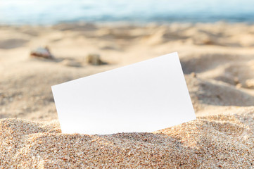 Blank card on sand at sea beach.