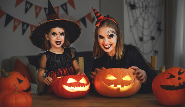 family mother and child daughter in costumes and makeup to halloween with pumpkin in   dark