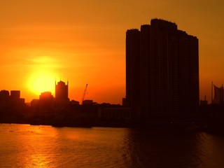 Obraz premium Skyline and buildings of Saigon silhouetted against a beautiful sunset in the Mekong River.