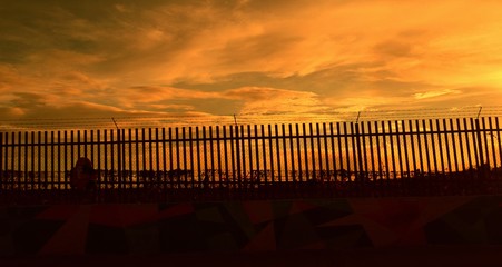 Panoramic sunset clouds with a fence in the foreground.