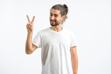 Fototapeta premium Happy man raised two fingers up. A young man shows a V gesture for good luck.