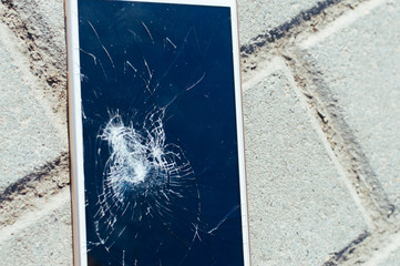 Broken smartphone on the asphalt close up. Glass replacement.