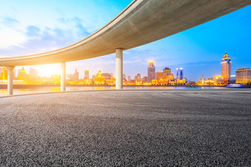 Empty asphalt road and modern city buildings in Shanghai at sunset