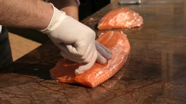 Chef is removing fish bone from salmon with tweezer