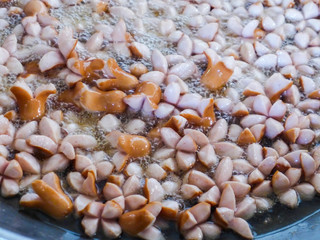 Fried sausages in boiling oil in a saucepan.