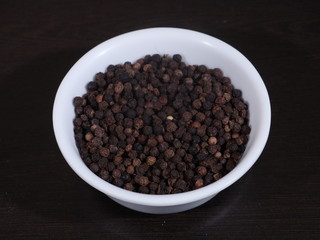 A pile of black pepper isolated on white background,Close up of black peppercorns or kali mari on wooden surface with its extracted herbal beneficial oil, Black Pepper, Kali Mirch,