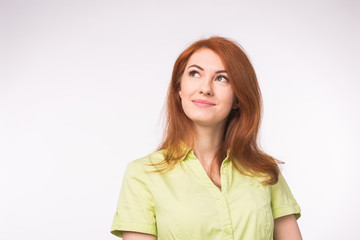 Obraz premium Attractive thinking red-haired woman on white background with copy space