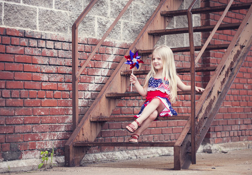 Portrait of smiling little girl with pinwheel sitting on stairs - Powered by Adobe