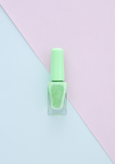 Light green nail polish on blank paper with blue color, space for design, beauty concept.