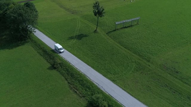 Aerial - High angle tracking shot of a white van driving and transporting cargo