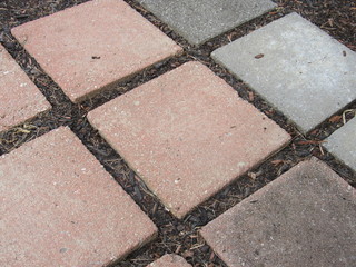 A stone tile walkway with mulch and dirt between the cracks 