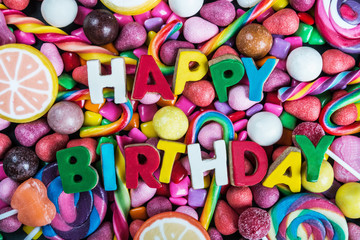 Fototapeta na wymiar background from variety of sweet, lollipops, chewing gum, candies, marshmallows and the words birthday. congratulations for the holiday
