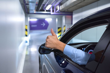 Big, a finger - gesture of the happy driver, against the background of the parking.