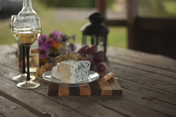 wine in a bottle,a glasses of white wine, grapes,various cheese and ,blue cheese,cheese Camembert, a bouquet and a lantern on the old table