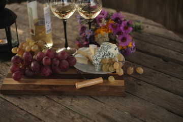 wine in a bottle,a glasses of white wine, grapes,various cheese and ,blue cheese,cheese Camembert, a bouquet and a lantern on the old table