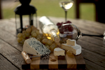 wine in a bottle,a glasses of white wine, grapes,various cheese and ,blue cheese,cheese Camembert, a bouquet and a lantern on the old table