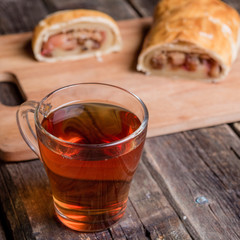 Apple strudel on wooden board served with tea