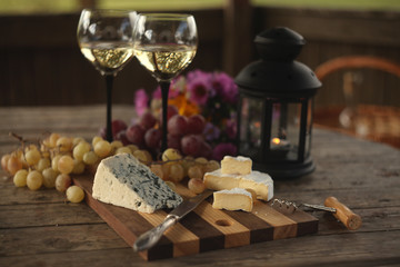 wine in a bottle,a glasses of white wine, grapes,various cheese and ,blue cheese,cheese Camembert, a bouquet and a lantern on the old table