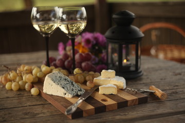 wine in a bottle,a glasses of white wine, grapes,various cheese and ,blue cheese,cheese Camembert, a bouquet and a lantern on the old table