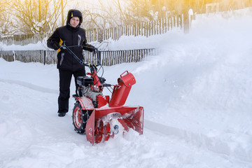 young man removes snow with a snowplower