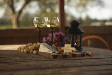 wine in a bottle,a glasses of white wine, grapes,various cheese and ,blue cheese,cheese Camembert, a bouquet and a lantern on the old table