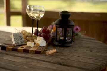 Fototapeta na wymiar wine in a bottle,a glasses of white wine, grapes,various cheese and ,blue cheese,cheese Camembert, a bouquet and a lantern on the old table