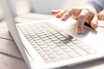 Hand clicking on laptop keyboard. Hand and notebook on table in the park