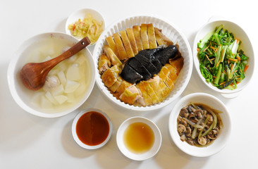 Top view of a few dishes of Chinese cuisine on a white table including chicken, radish soup, fried green vegetables,and fried mushrooms at a festival time.