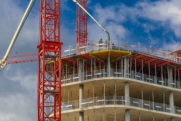 Rohbau eines B&uuml;rogeb&auml;udes mit Ger&uuml;st und zwei roten Kr&auml;nen und einer Betonppumpe