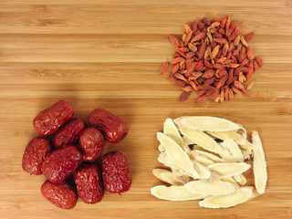 Top view of red dried jujube (called red date or Chinese date) and goji berry (called wolfberry) and Astragalus slices on brown  wooden background.Those are traditional Chinese herbal medicine.