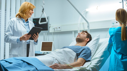 Friendly Female Doctor Visits Smiling Recovering Man who is Lying in Bed, She Asks Him Questions and Fills Medical Chart, Nurse Checks His Vital Signs.