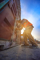 foreman worker labor or stvedore works on checking safety and sealing door of containers unit, safety before shifting to the ship, loading shipment security