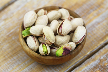 Closeup of delicious pistachio nuts in small wooden bowl
