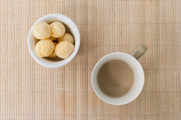 Pao de Queijo (Bread Cheese) and cup of coffee with milk on wooden table.