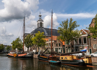Traditional wooden sailing ships in water channel. Church on background. Old historic harbor of Schiedam, The Netherlands