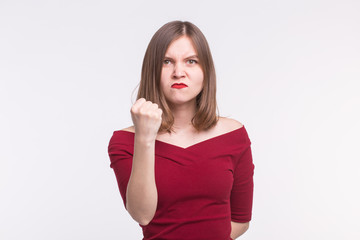 Portrait of angry young woman showing a fist on white background