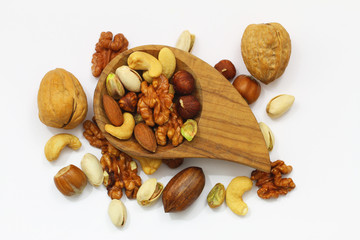 Selection of nuts: walnuts, hazelnuts, pistachio nuts, pecan nuts, cashew nuts, almonds with and without nutshell in bamboo bowl on white background
