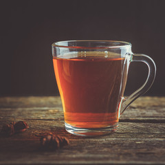A glass cup of black tea on a wooden table.